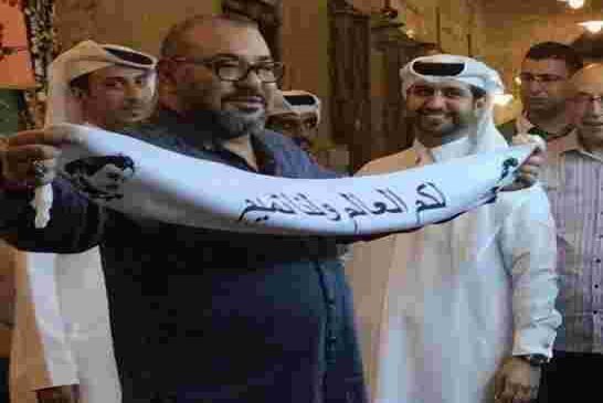 ملك المغرب يشعل مواقع التواصل بسبب رفع وشاحا كتب عليه “لكم العالم ولنا تميم”